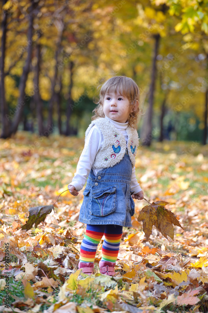 Little girl holding leaves standing in yellow forest Little girl holding leaves standing in yellow forest