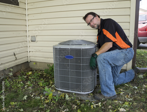 Repairman Cleaning Outside Air Conditioner Unit Grill