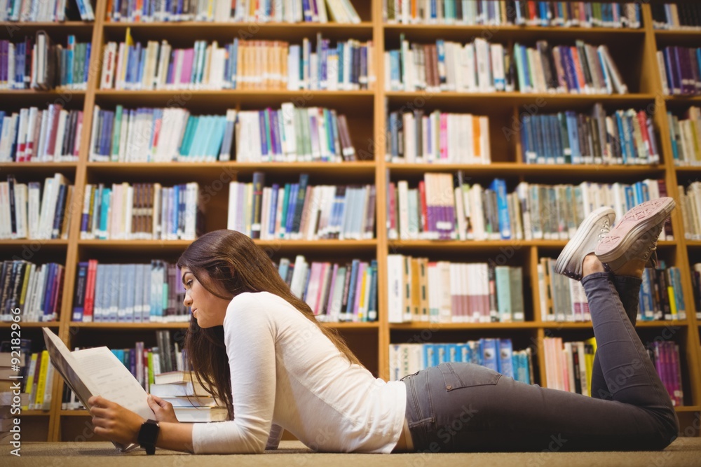 Side view of woman studying while lying on floor Side view of woman studying while lying on floor