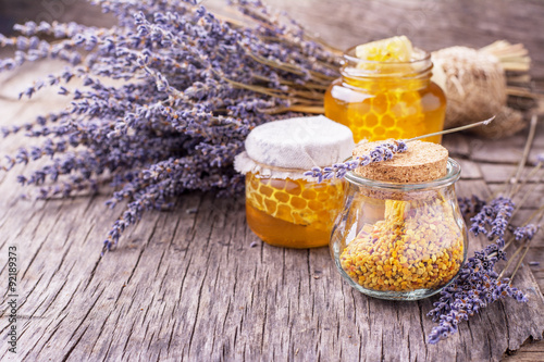 Arrangement of small glass jars with lavender honey, honeycombs and bee pollen