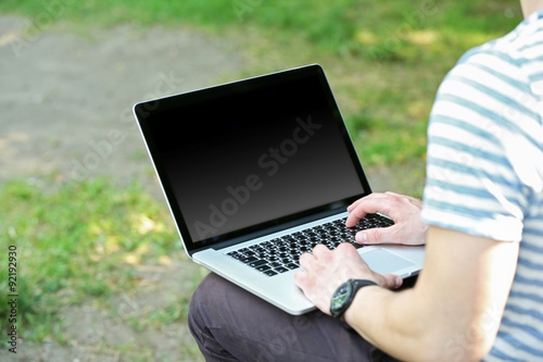 Young man with laptop outdoors