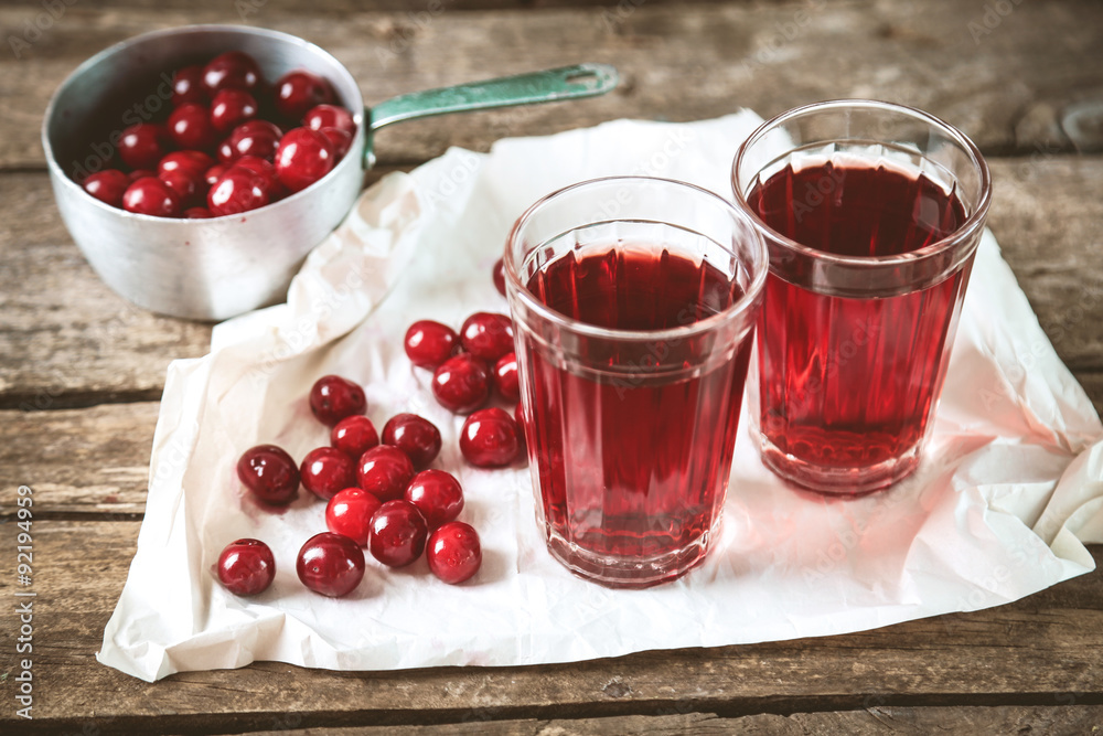 Two glasses with cherry juice on table, on wooden background Two glasses with cherry juice on table, on wooden background