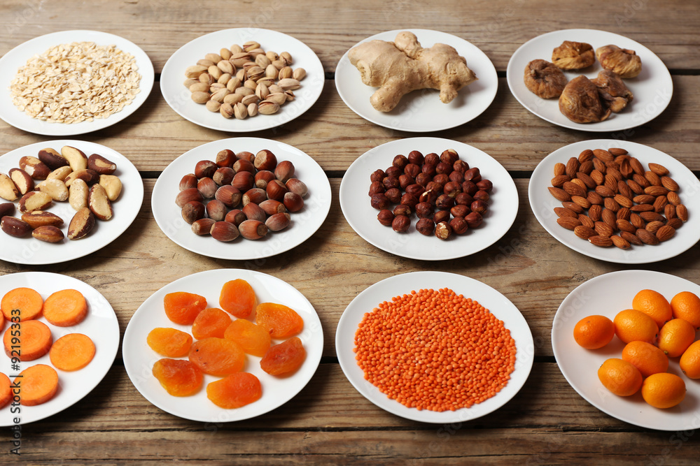 Different products on saucers on wooden table close up