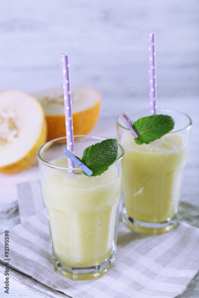 Glasses of melon cocktail on white wooden background
