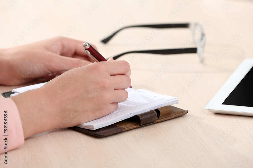 Fototapeta premium Woman write on notebook on workplace close up