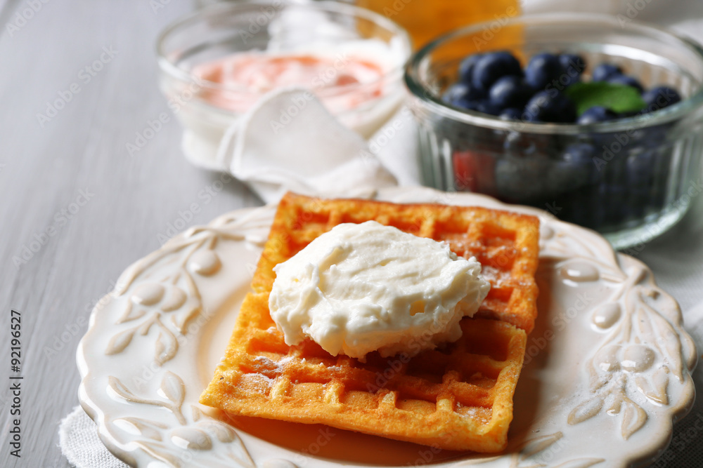 Sweet homemade waffles on plate, on color wooden background Sweet homemade waffles on plate, on color wooden background