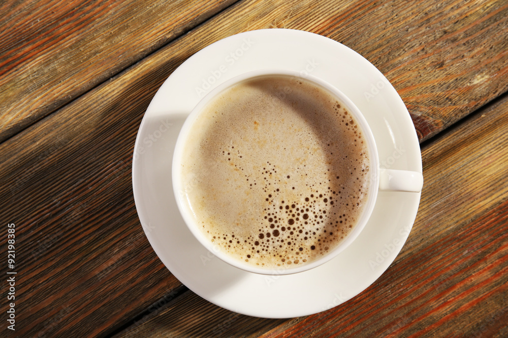 Cup of coffee with foam on wooden table, top view Cup of coffee with foam on wooden table, top view