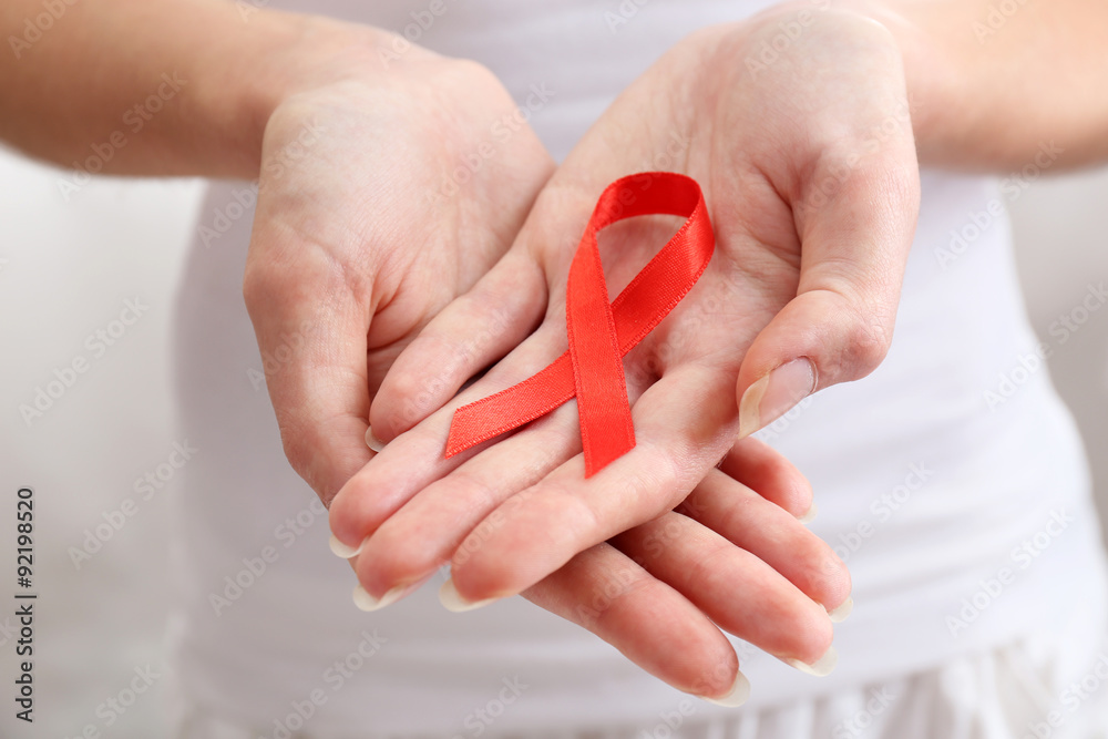 Female hands holding red ribbon sign, closeup Female hands holding red ribbon sign, closeup