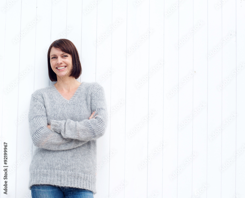 Mature woman smiling against white wall