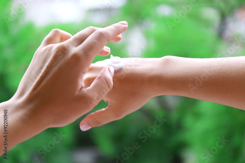 Women applying cream on her hands outdoor