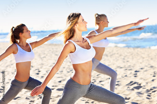 Group of women practising yoga on the beach