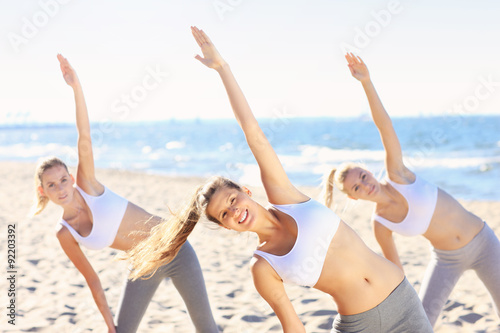Group of women practising yoga on the beach