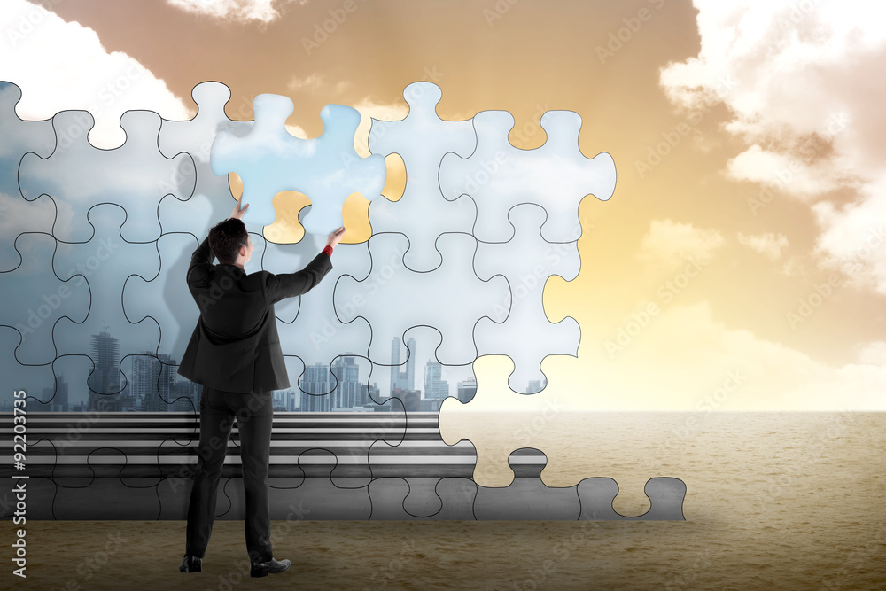 Business person building puzzle of city in the desert
