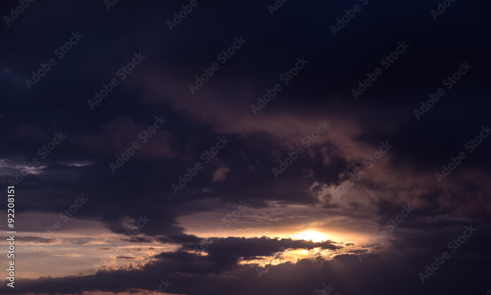 Dramatic sunset sky with dark clouds.