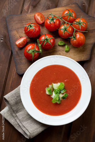 Gazpacho soup and fresh tomatoes on a rustic wooden background