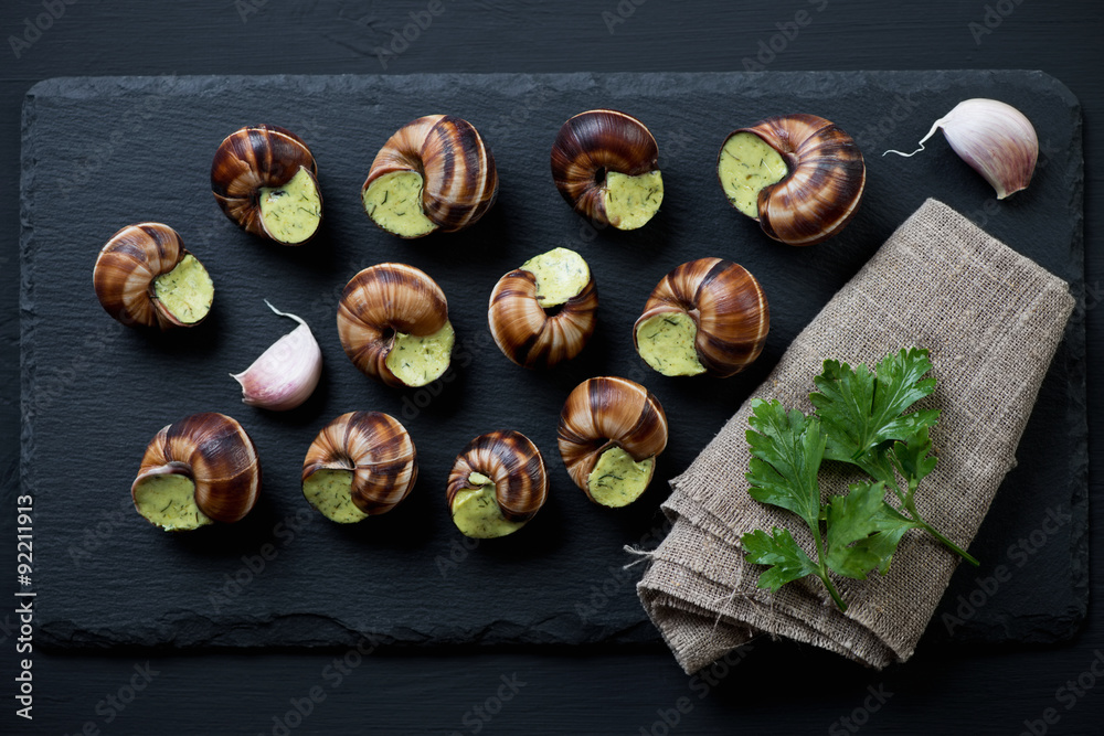 Stone slate plate with uncooked escargots de bourgogne, top view Stone slate plate with uncooked escargots de bourgogne, top view
