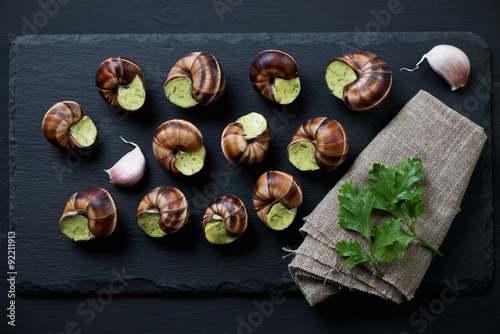 Fototapeta Naklejka Na Ścianę i Meble -  Stone slate plate with uncooked escargots de bourgogne, top view