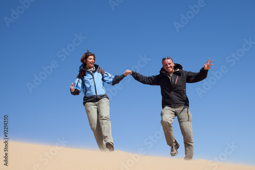 Coppia felice che corre sulla sabbia del deserto