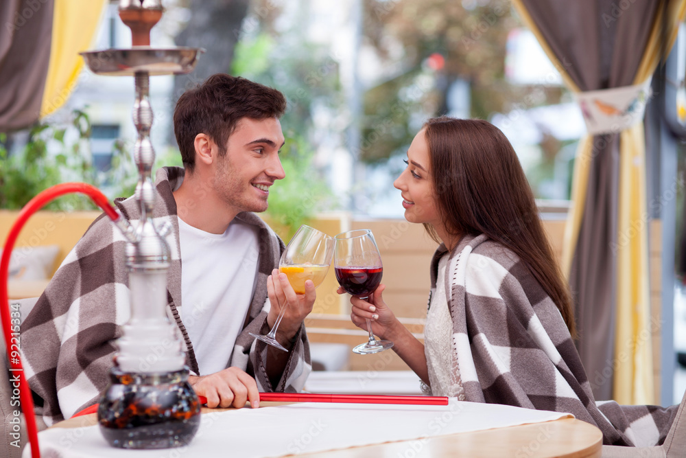 Pretty loving couple is relaxing with water pipe in cafe