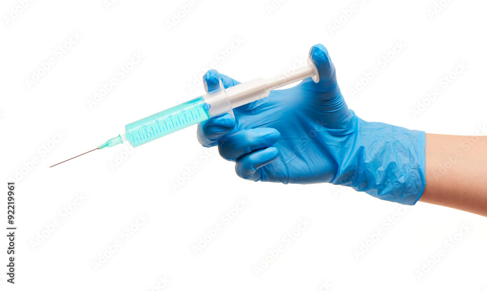 Close up of female doctor's hand in blue sterilized surgical glove with plastic medical syringe filled with blue drug against white background Close up of female doctor's hand in blue sterilized surgical glove with plastic medical syringe filled with blue drug against white background