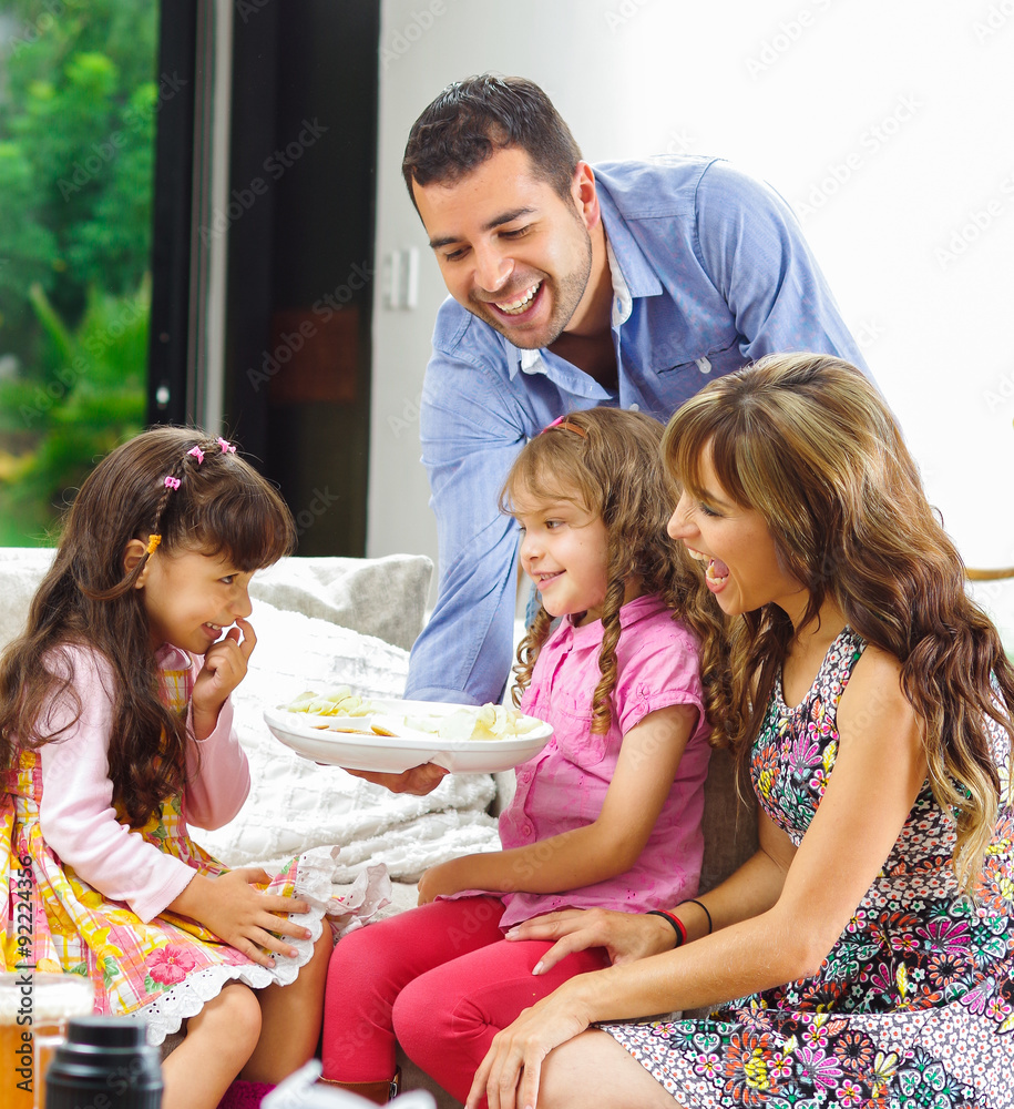 Hispanic parents with two daughters eating from a tray of potato Hispanic parents with two daughters eating from a tray of potato