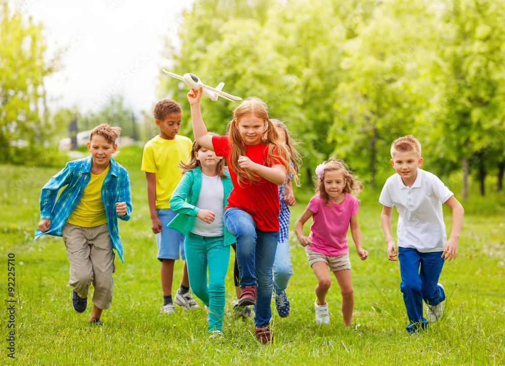 Moving girl holds airplane toy and kids behind Moving girl holds airplane toy and kids behind