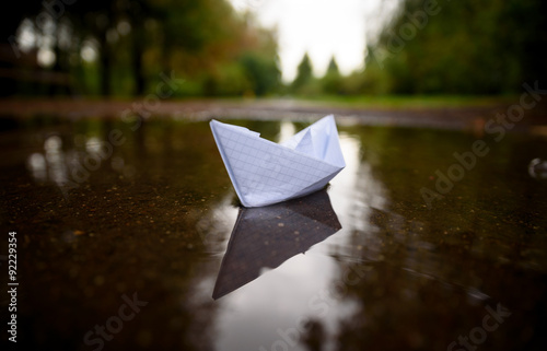 Paper boat floating on water in autumn park