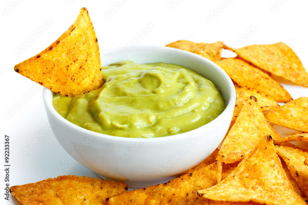 Round white bowl of guacamole dip surrounded with tortilla chips Round white bowl of guacamole dip surrounded with tortilla chips