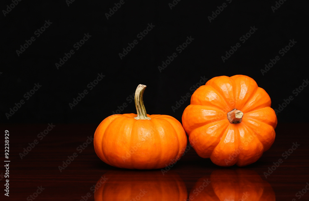 Two tiny pumpkins over black background. Halloween