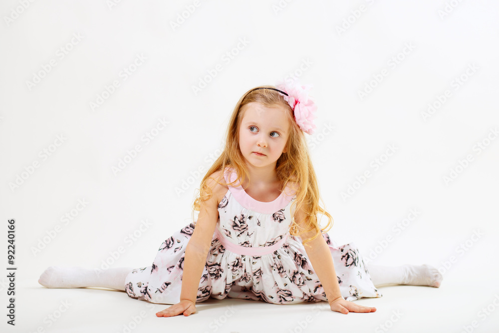 Fototapeta premium Little blond girl sitting on the twine in front of white backgro