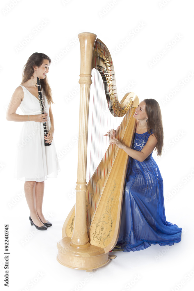 Obraz premium two young women in studio with harp and clarinet against white b