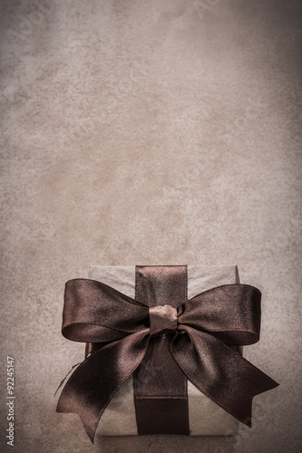 Wrapped gift box with tied ribbon paper on vintage background