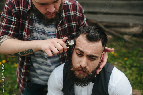 barber shaves a bearded man