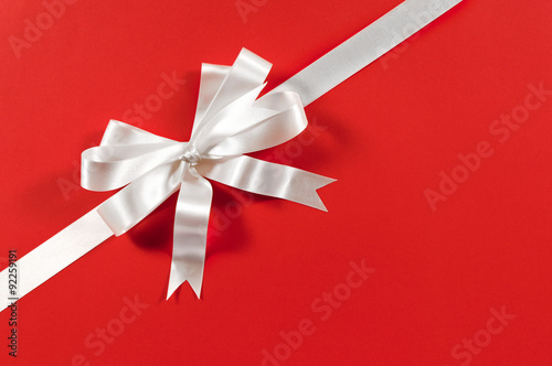 White gift ribbon and bow corner diagonal for birthday or christmas present decoration on red wrapping paper background photo