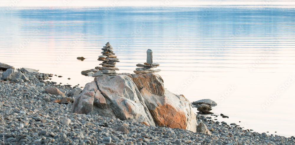 Obraz premium Two sculptures of balancing rocks on a lake shore