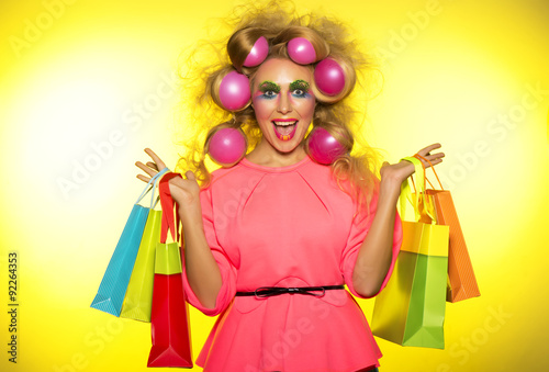 Girl with bright makeup with balloons in hair and purchase in hands