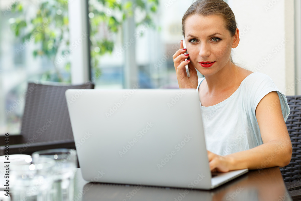 Attractive woman sitting in a cafe with a laptop and talking on Attractive woman sitting in a cafe with a laptop and talking on
