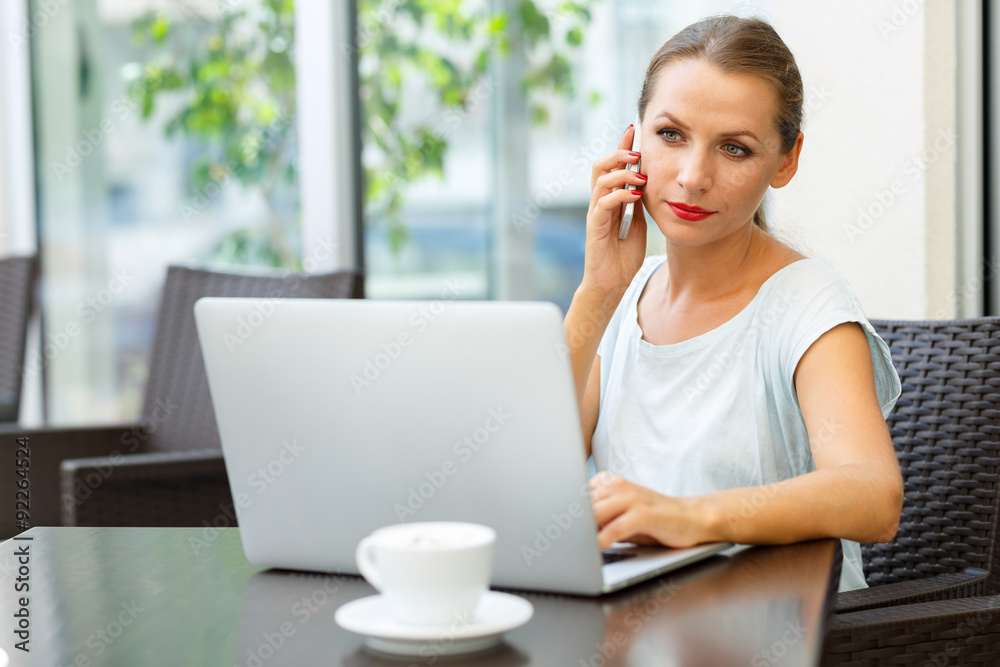 Attractive woman sitting in a cafe with a laptop and talking on Attractive woman sitting in a cafe with a laptop and talking on
