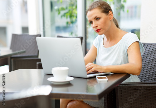 Young business woman sitting in a cafe with a laptop and coffee