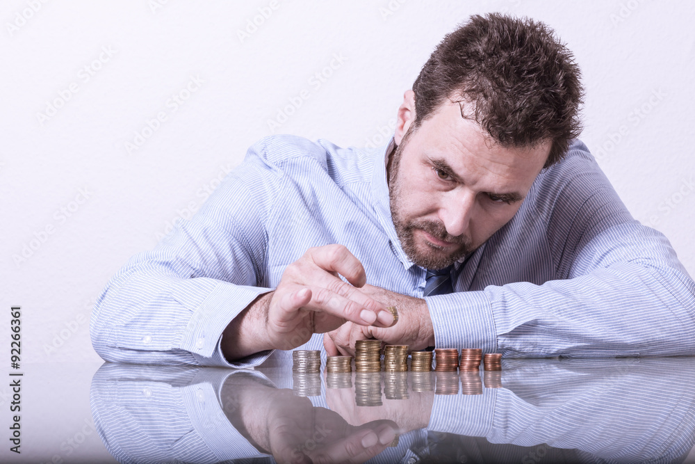 Business man counting money, stacks of coins on office desk. Mat