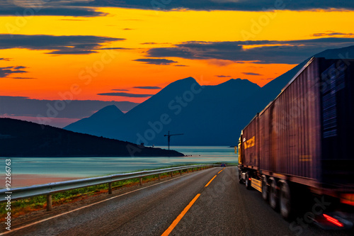 Truck traveling on the road at sunset.