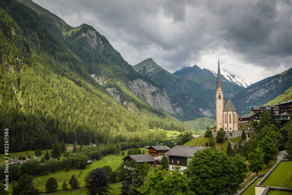 Rural landscape of Heiligenblut with St Vincent Church in Carynthia and Grossglockner (3797 m. elevation) highest mountain from Austria in background.