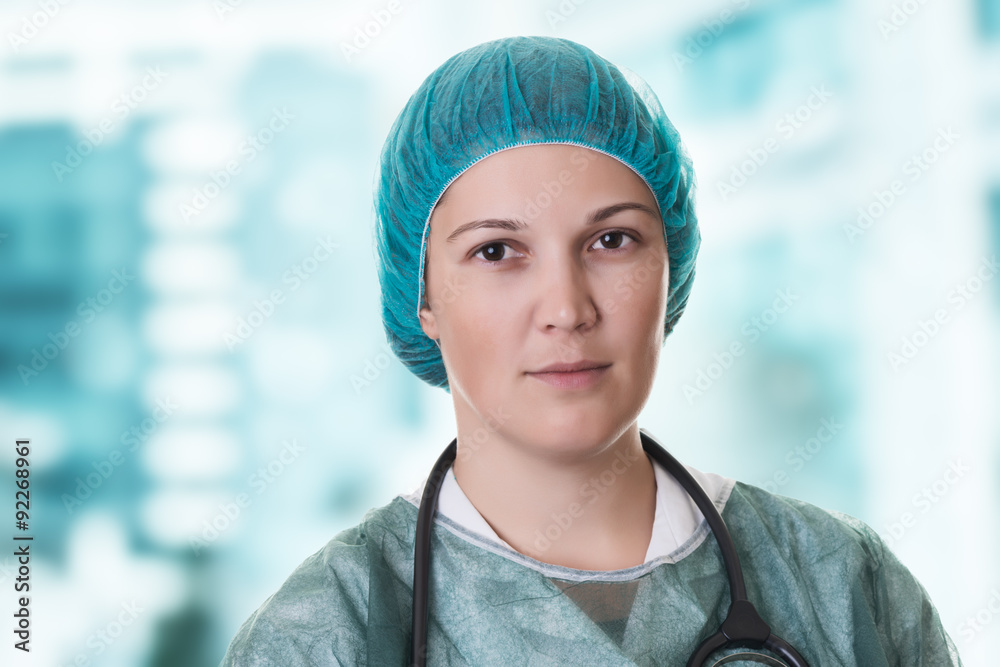 Hospital indoor closeup portrait of female doctor with stethoscope and  bonnet on creamy blue background. Stock Photo | Adobe Stock