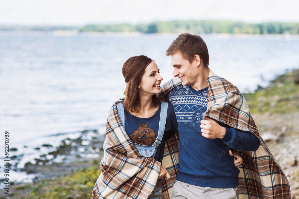 Young couple in love wrapped in plaid on a beach Young couple in love wrapped in plaid on a beach