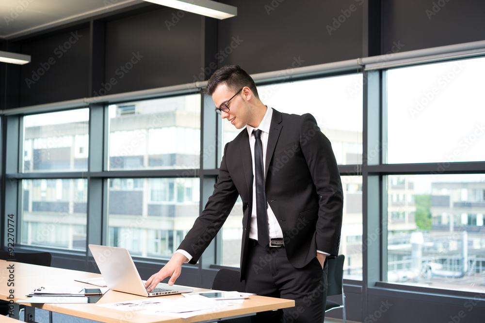 Young businessman in shirt and tie working on laptop at the offi Young businessman in shirt and tie working on laptop at the offi