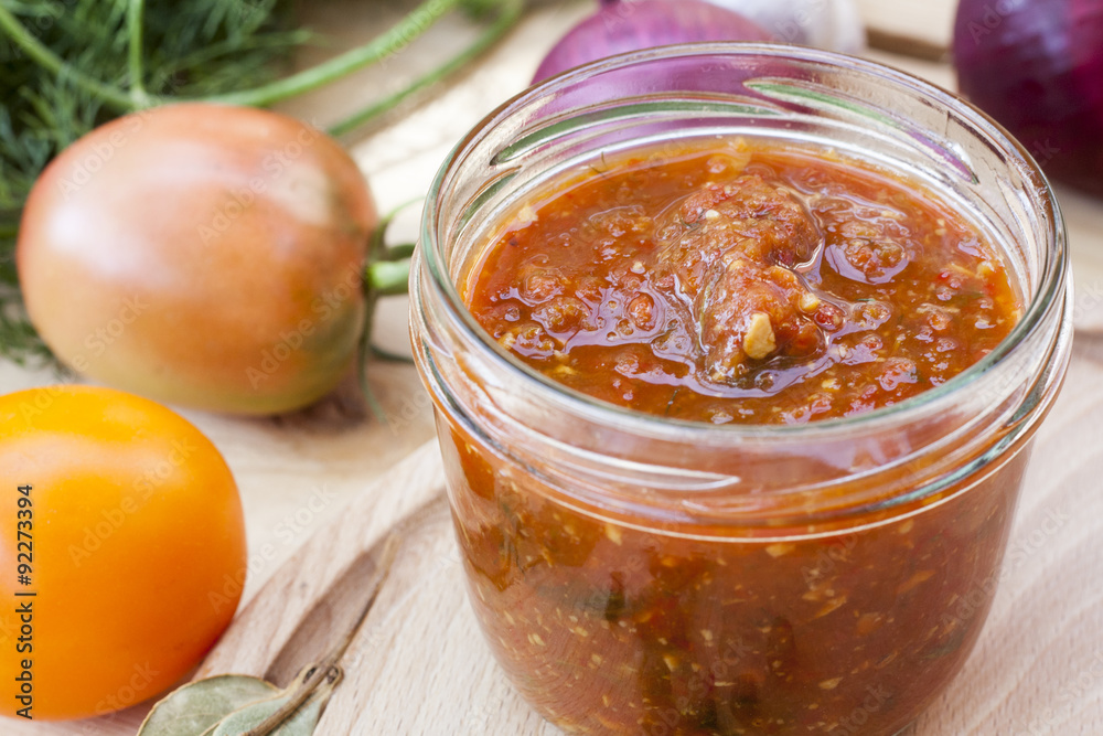 Homemade tomato sauce in glass jar with fresh tomatos, garlic, onion, herbs and spices Homemade tomato sauce in glass jar with fresh tomatos, garlic, onion, herbs and spices