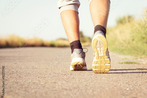 man's running legs on the paved road