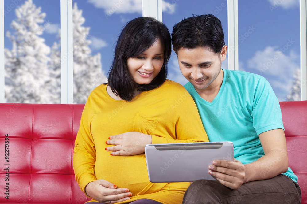 Fototapeta premium Man with pregnant wife using tablet