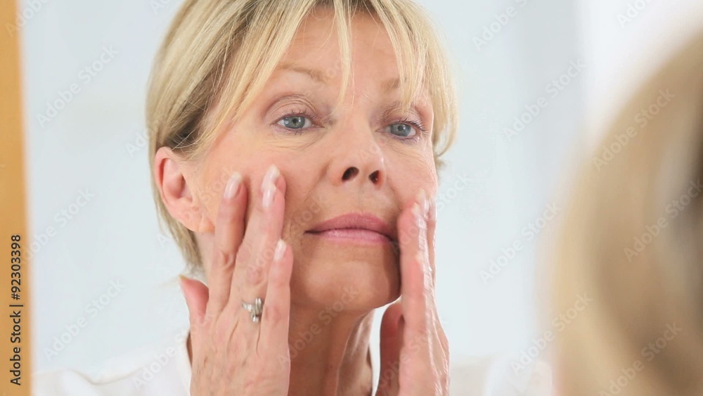 Senior woman applying cosmetic lotion on her face