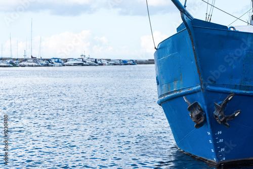 Blue bow of an old fishing boat with modern boats on a background